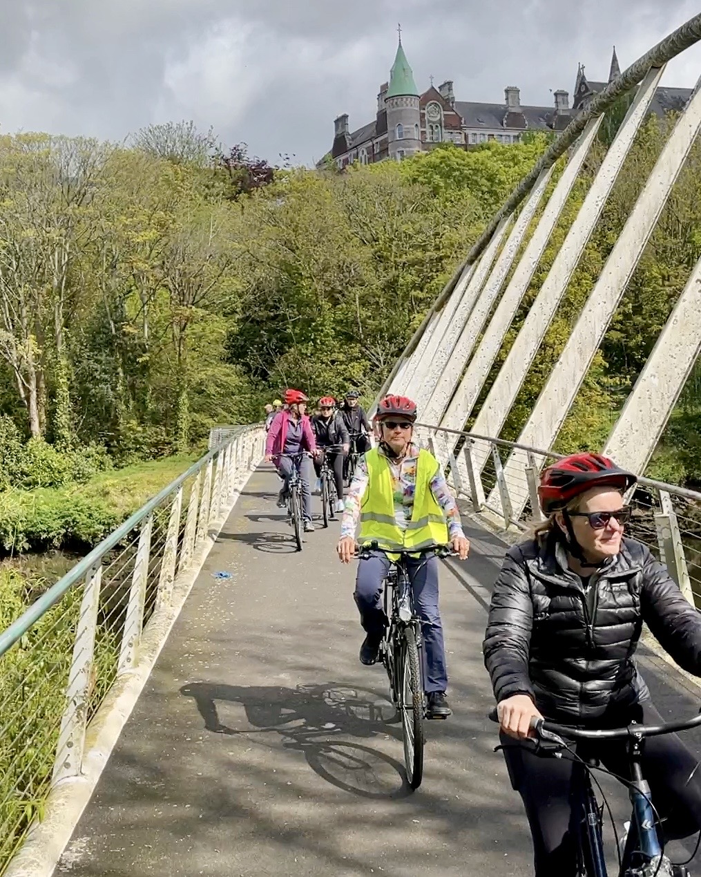 A group cycling together across a bridge over the River Lee in Cork City