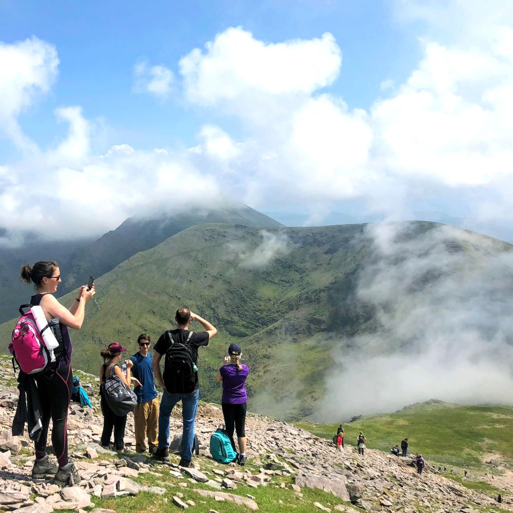 Hikers stopped on a high ridge taking photographs above the clouds