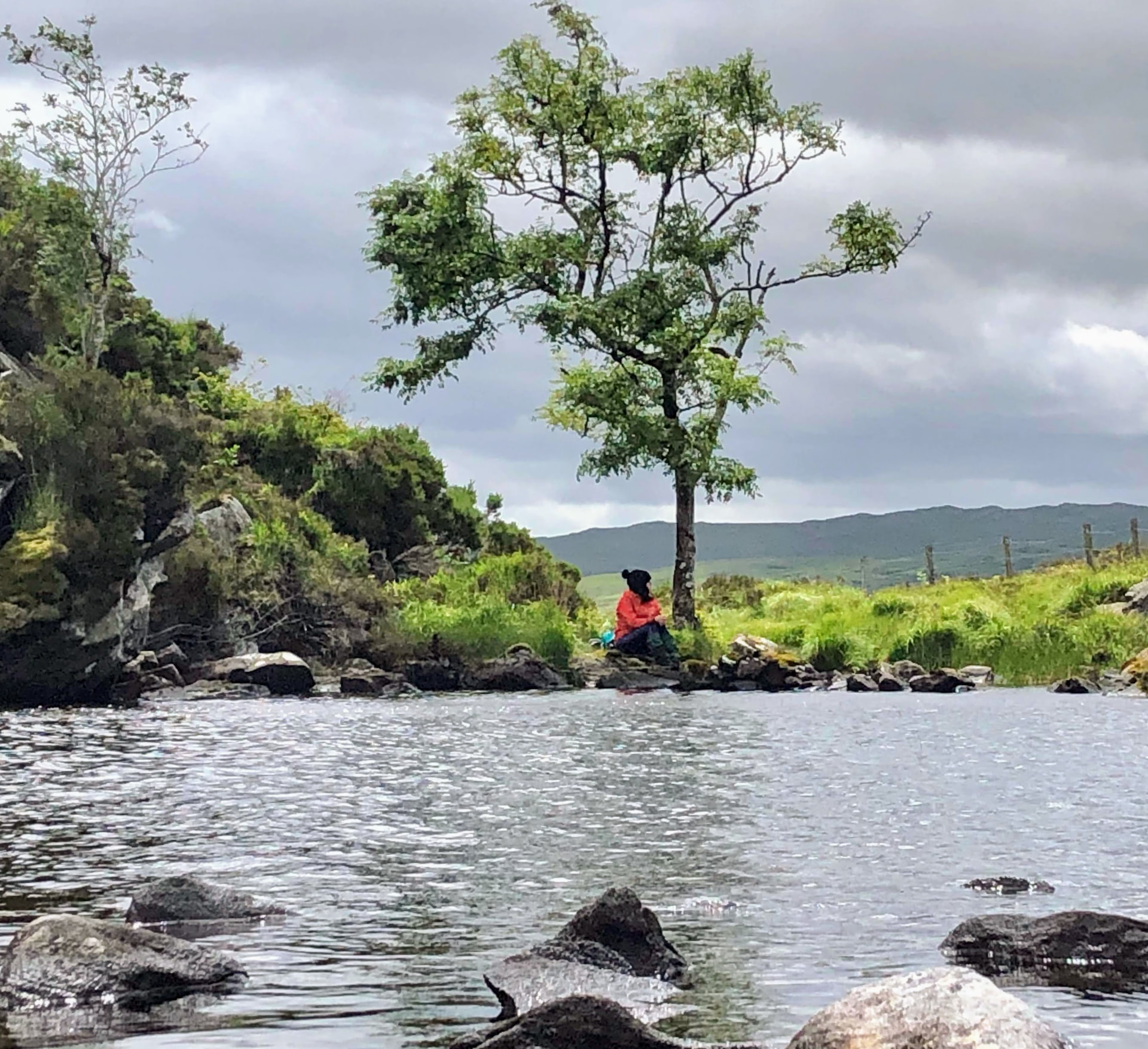 Hiker resting beside a mountain lake in Munster