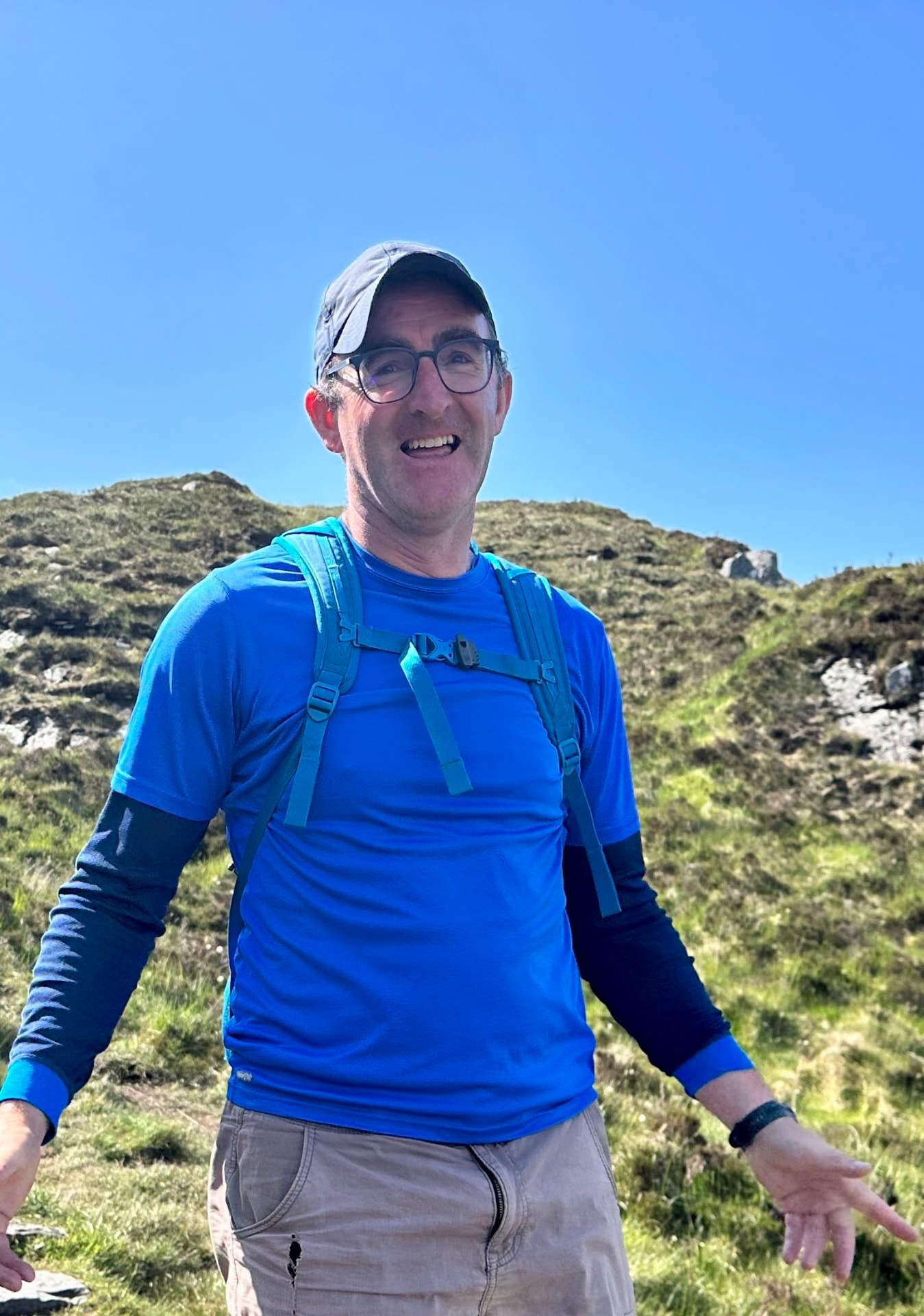 James Foley in a blue top on a grassy mountainside on a clear day