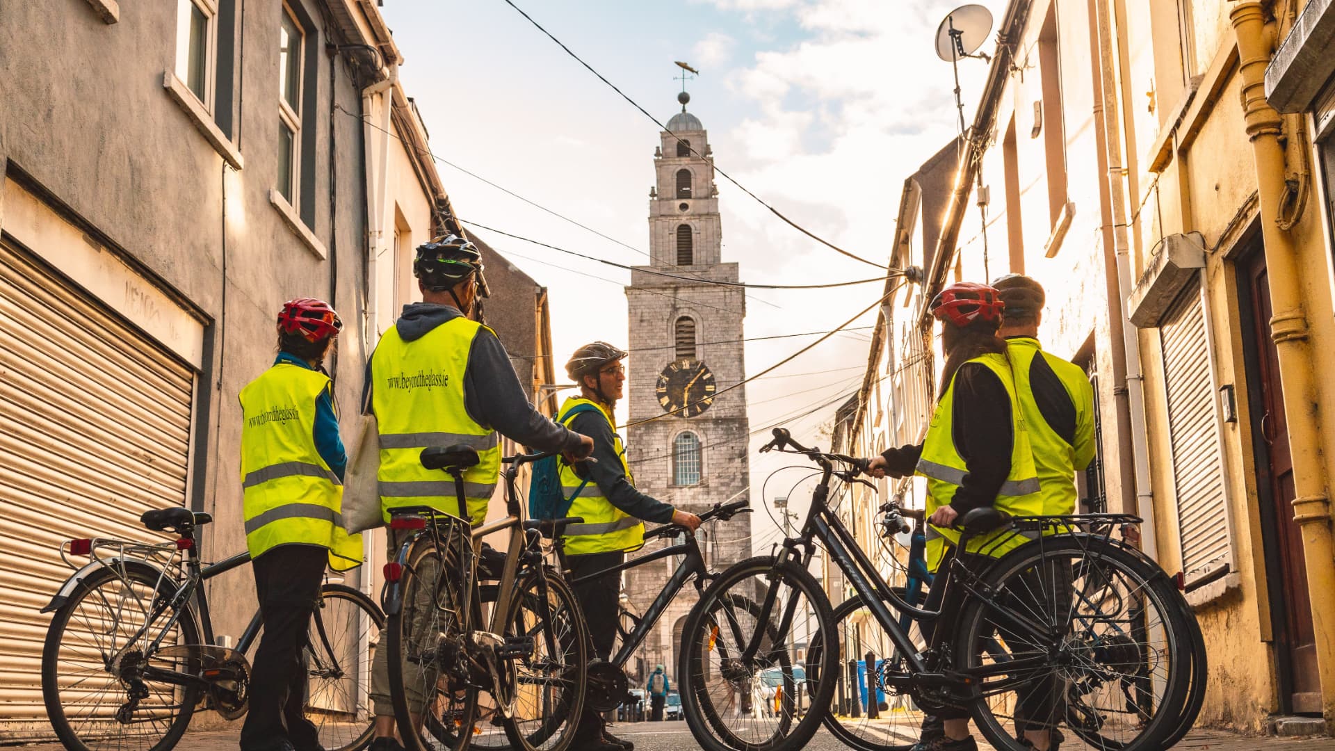 Cyclists stopped on a Cork city street with Shandon Bells tower in the background