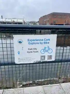 Small Experience Cork – Explore by Bike sign fixed to the riverside railings on St Patrick's Quay